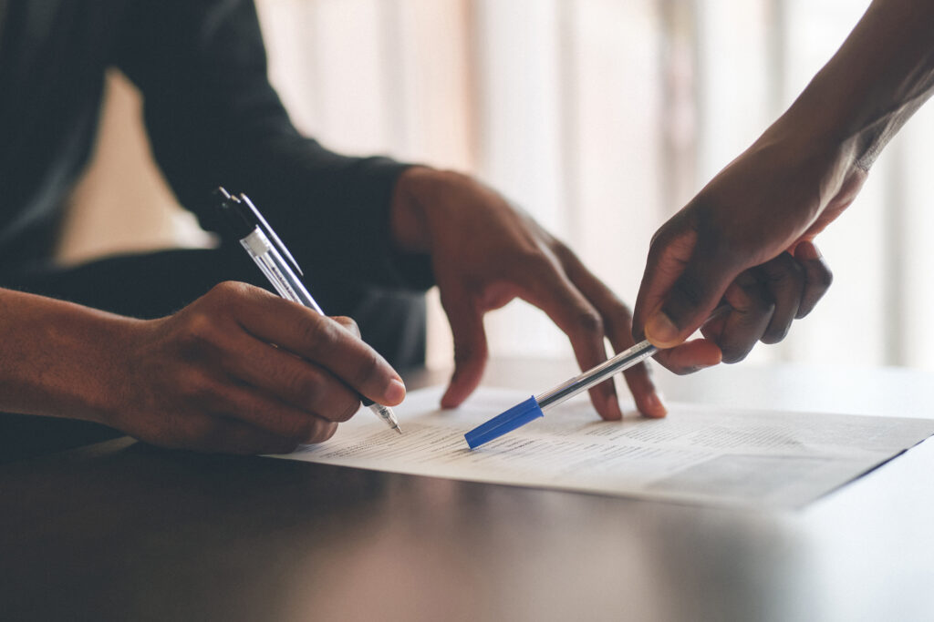 Close-up of two people reviewing and signing a billing document.