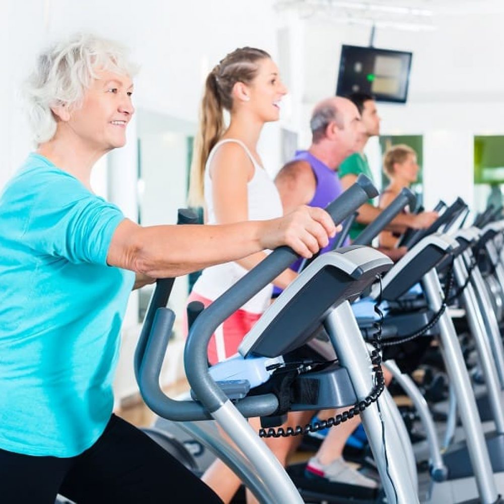 Group of people on elliptical trainer exercising in gym